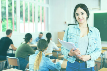 Fototapeta premium Portrait of young smiling schoolgirl who is satisfied assessment in the class.