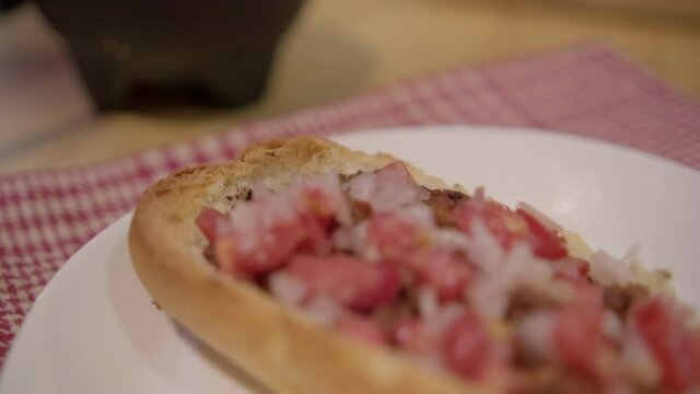 Traditional Mexican mollete on a plate above white and red checkered napkin