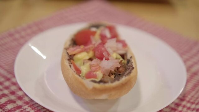 Traditional Mexican mollete on a plate above white and red checkered napkin