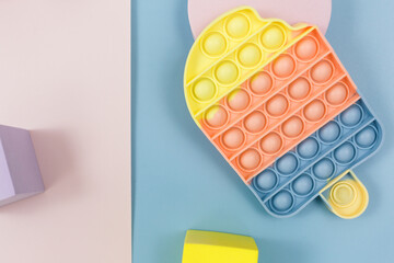 Popular silicone pastel anti-stress pop it toys and geometric shapes for a child on blue pink background. Trendy Sensory Fidget Toy. Funny Bubble suitable for relieving stress for adults