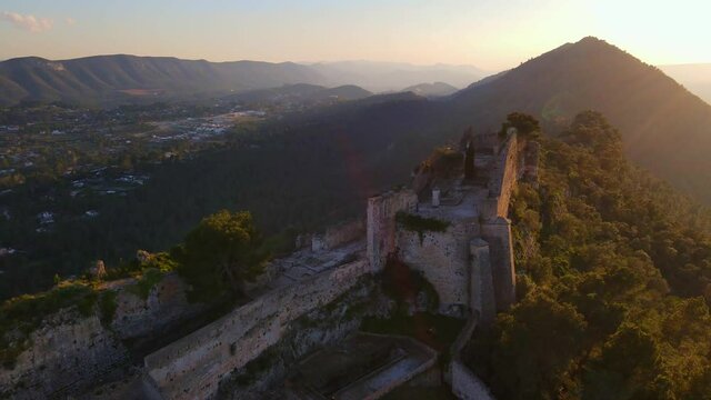 The impressive walls of the castle of X&aacute;tiva on the mountains illuminated by the sun.
