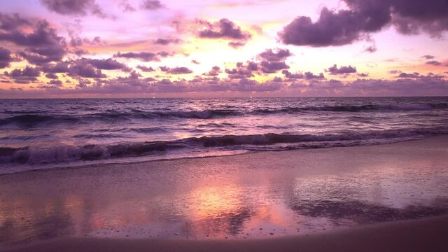 Dramatic sea sunset or sunrise Burning purple sky and shining white waves crashing on sandy shore Beautiful light reflection on sea surface Amazing landscape or seascape background