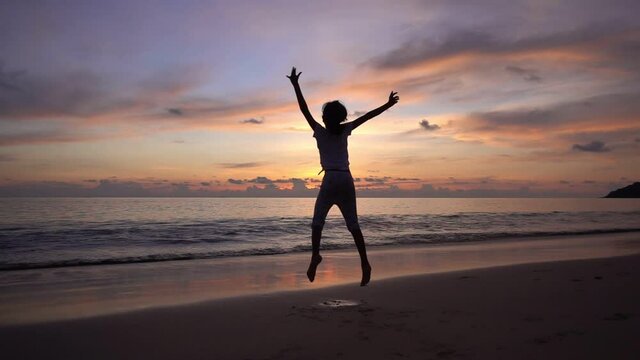 Silhouette Asian teen girl 6 years old jumping on beach at sunset raising arms on beach enjoying Amazing sunset or sunrise on summer travel vacation holiday Happiness travel and bliss concept video