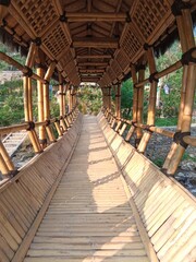 A sturdy bamboo bridge with a covering roof