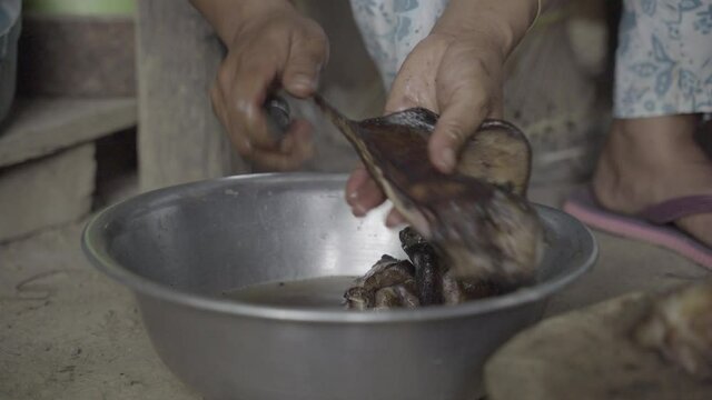 Hog ears seared on open flame are scraped and washed by Manipuri chef