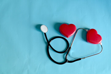 Top Views of Heart-shaped plastic box with Black Stethoscope isolated on blue background with copy space at Thailand. Medical device concept. Selective Focus.