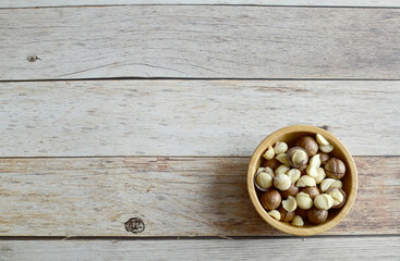 Fototapeta na wymiar Top Views of Macadamia Nuts in a wooden bowl isolated on the wooden background, Healthy Food Concept.