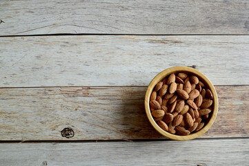 Top Views of Almond Nuts in a wooden bowl isolated on the wooden background, Healthy Food Concept.