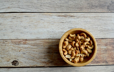 Top Views of Cashew Nuts in a wooden bowl isolated on the wooden background, Full depth of field.