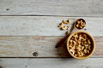 Top Views of Cashew Nuts in a wooden bowl and wooden spoon isolated on the wooden background, Full depth of field.