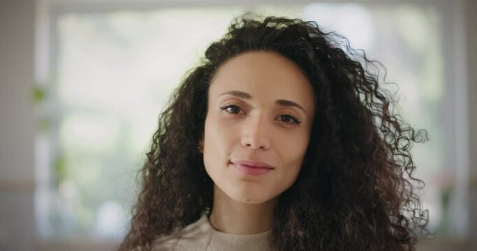 Portrait of a young woman with curly hair smiling. Close up, slow motion. 