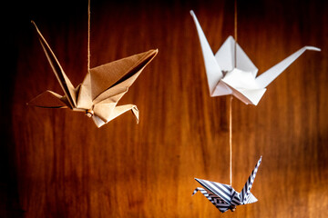 Three origami swans hanging from the roof with a wooden background