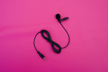 Obraz na płótnie Canvas clip on mic on pink background. clip on microphone with wire captured on pink. minimal object shot.