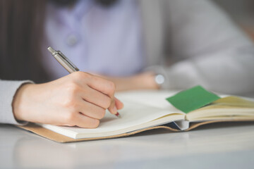 Stock photo of a young teenage woman Asian college student in student uniform studying and writing on a notebook in a university classroom