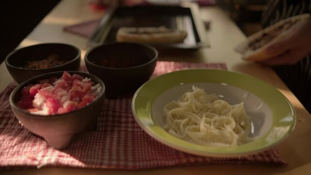 Black bowls of pico de gallo and plate of cheese above checkered tablecloth