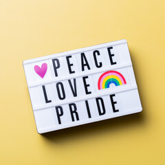 Peace love pride text, rainbow lgbtq flag against yellow background