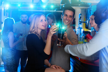 Group of friends clinking glasses with cocktails at night club