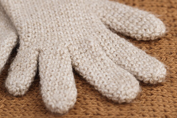 Close-up detail of part of cream-colored wool glove, crocheted. Winter clothing.