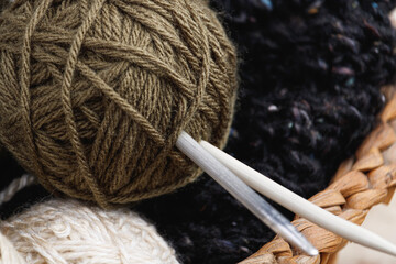 Flat detail of needles pricked in green wool bun. Concept of knitting, handicrafts, hobbies, household chores.