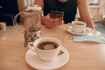 A man using smartphone to pay at a cafe, showing the concept of wireless payment and the new normal during the covid-19 pandemic