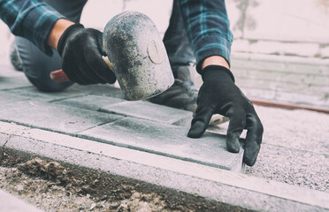 Worker lining paving slabs path