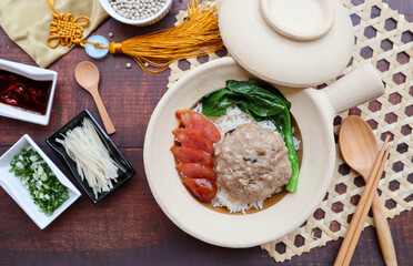 Steamed pork cake with salted fish over rice in a claypot of wood table - Chinese food called Yee Jeng Yook Baeng or Xian Yu Zheng Rou Bing at top view