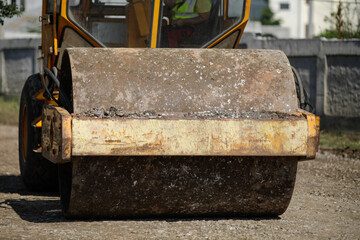 Shallow depth of field (selective focus) details with a heavy vibrator roller (vibratory compactor, compaction roller) on the construction site of a road.