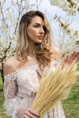  Girl in a white dress stands next to a blooming tree