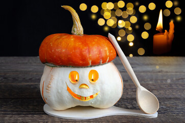 A creepy smiling Halloween pumpkin with a burning candle flame. Orange nightmare on a wooden table