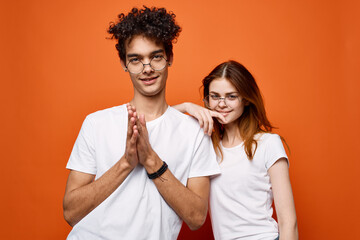 young couple in white t-shirts and glasses fun fashion orange background