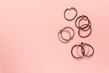 Set of multicolored hair ties on pink background, space for text