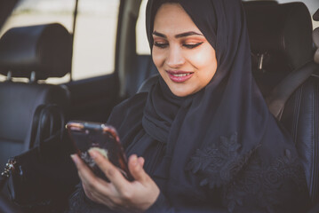 Beautiful woman in Dubai wearing abaya traditional female dress driving the car. Concept about uae...
