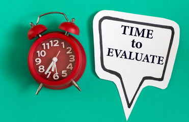 TIME TO EVALUATE - words on a white note on a green background with a red alarm clock