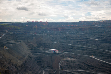 heavy dump trucks, excavators, diggers and locomotives extracting iron ore in deep quarry