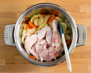 Vegetables and raw chicken in a saucepan. Preparation for cooking broth