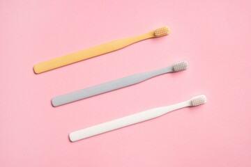 Pastel color toothbrushes on pink background .Simple composition for cleaning teeth and morning routine