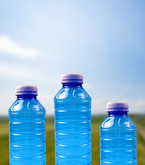 Plastikowe butelki na tle nieba i pola uprawnego. Ratowanie środowiska poprzez segregacje odpadów.  - obrazy, fototapety, plakaty