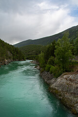 Mountain river in the mountains. Otta river, Norway. The turquoise color comes from algae in melted snow. Vertical photo. Copy space. The river is known for rafting.