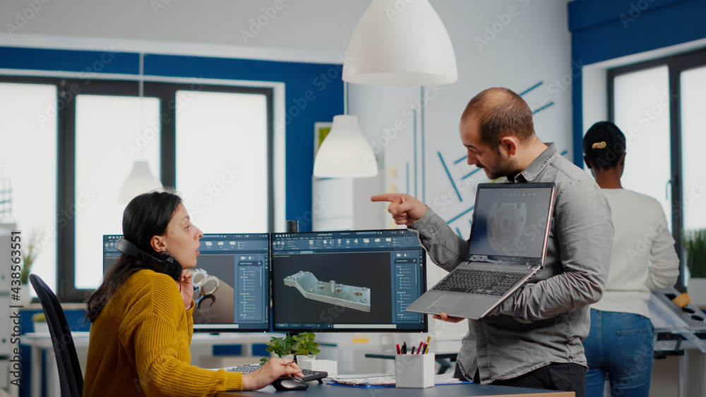 Wall mural man project supervisor holding laptop and pointing on display showing to woman industrial engineer w