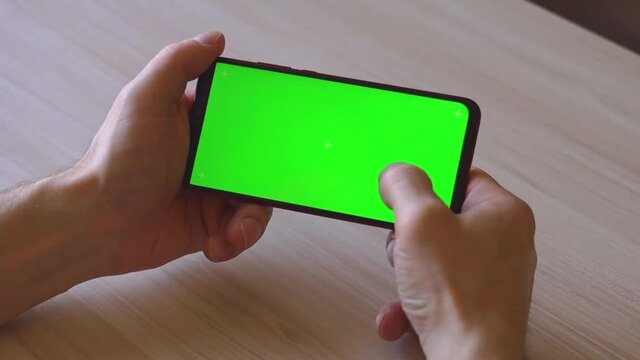 A mobile phone with a green screen. They hold his hands.