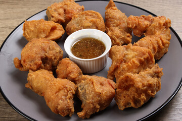 Light battered deep fried chicken variety mix pieces pile flaky meat on grey plate honey garlic clear sauce in centre healthy fry