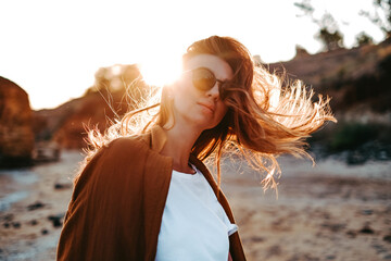 portrait of a beautiful girl at sunset. the wind develops hair harmony with nature on isolation, walks near the sea