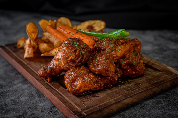 Tasty barbecued wings with french fries and vegetables