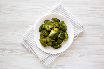 Homemade Roasted Broccoli with Salt and Pepper on a plate on a white wooden table, top view. Flat lay, overhead, from above.
