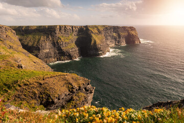 Amazing view on Cliff of Moher, county Clare, Ireland. Popular landmark with unparalleled scenery. Warm sunny day, Cloudy sky