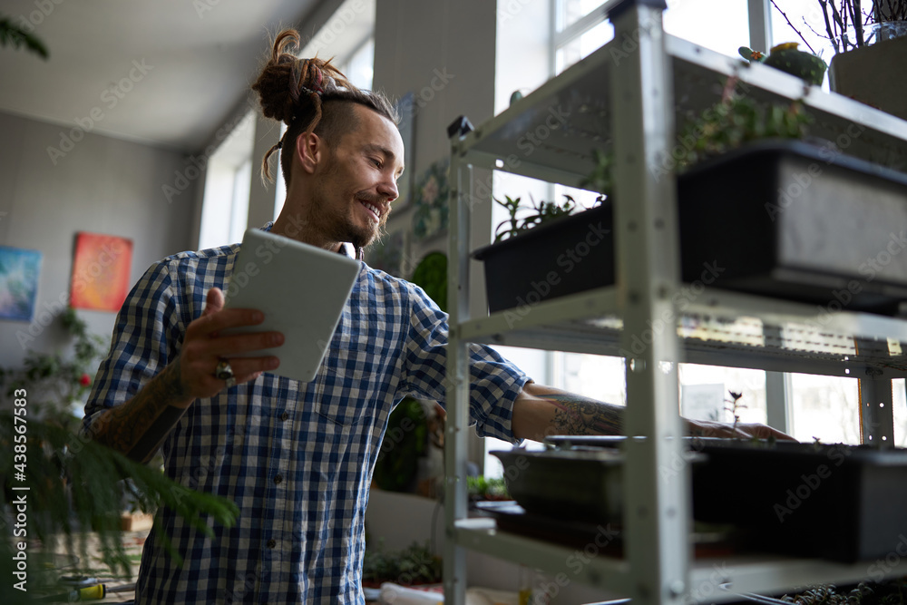 Wall mural handsome man using digital tablet computer and checking plants