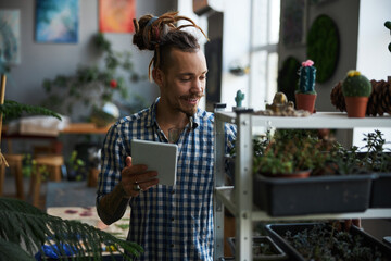 Cheerful man using digital tablet computer and checking plants