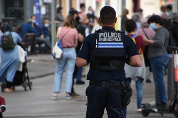 A policeman seen from behind watches people in the street