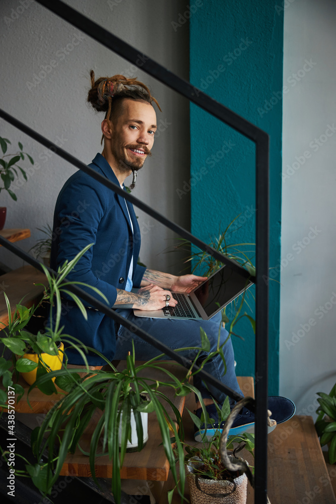 Wall mural Joyful young man using notebook at home