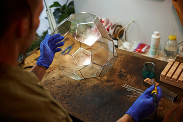 Male person making glass florarium in workshop